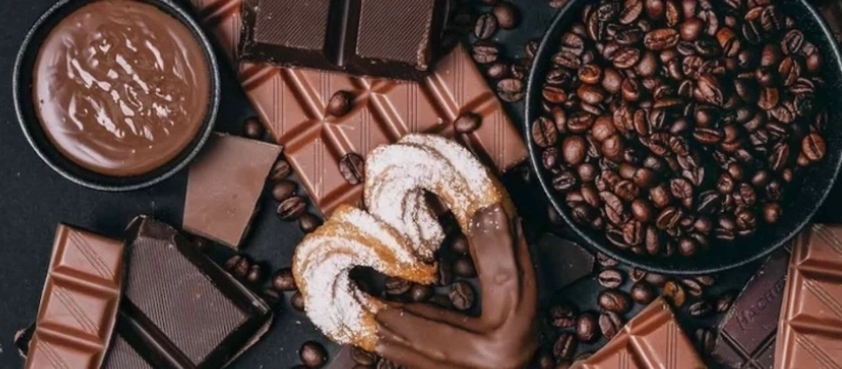 Schokolade, Kaffee, Gebäck und Schokoladensauce auf schwarzem Hintergrund