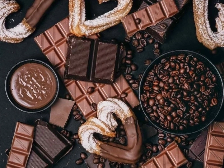 Schokolade, Kaffee und Gebäck auf dunklem Hintergrund. Süße Leckereien.
