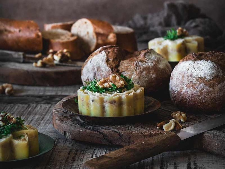 Brot, Kuchen, Walnüsse und Messer auf einem Holzbrett