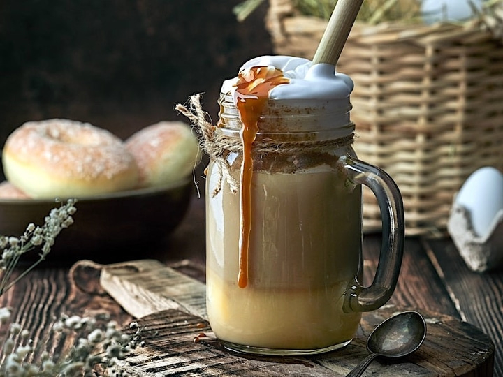 Kaffeegetränk mit Sahne und Karamell, Donuts, rustikale Holzoberfläche