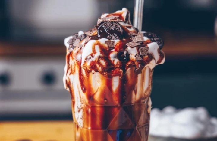 Ein köstlicher Eisbecher mit Schokoladensoße, Sahne und Keksen. Ein süßer Genuss.