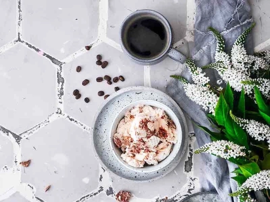 Kaffee, Eiscreme, Blumen und Kaffeebohnen auf einem Tisch