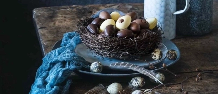 Ostereier in einem Nest auf einem Tisch mit blauer Serviette und Dekoration