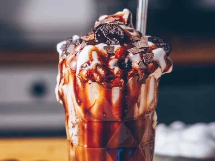 Ein köstlicher Eisbecher mit Schokoladensoße, Sahne und Keksen.
