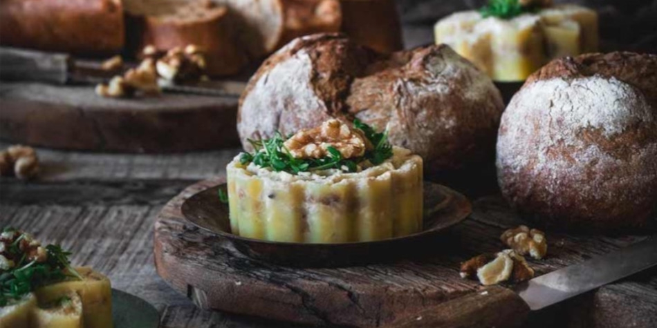 Köstliches Essen mit Brot, Nüssen und einem dekorativen Gericht auf einem Holzbrett.