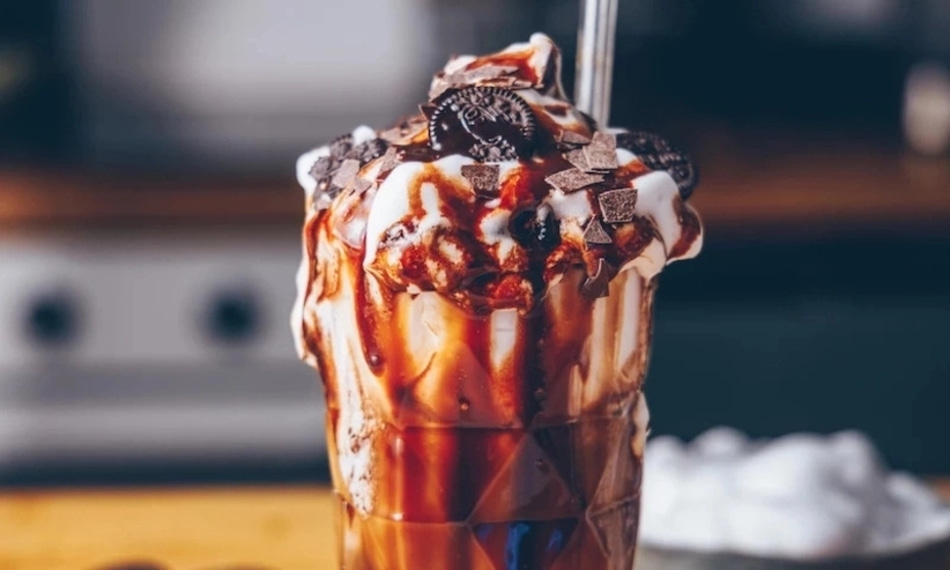 Ein köstlicher Eisbecher mit Schokoladensoße, Keksen und Schokoladenstückchen.