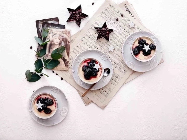 Drei Desserts mit Brombeeren und Sternen auf einem Tisch mit Noten und Dekoration.