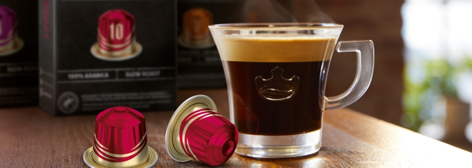 Kaffee in einer Tasse mit Kapseln und Verpackungen im Hintergrund