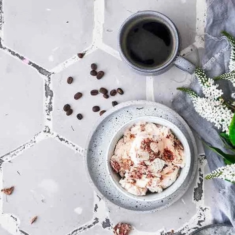 Kaffee, Eiscreme und Kaffeebohnen auf einem Tisch mit Blumen.