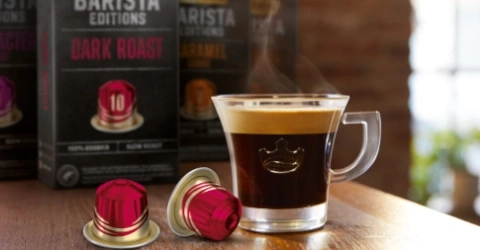 Kaffeetasse mit Espresso und Kaffeekapseln auf einem Holztisch